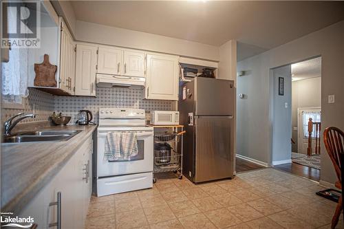 Kitchen featuring white cabinetry, sink, tasteful backsplash, light hardwood / wood-style floors, and white appliances - 96 Sixth Street, Midland, ON - Indoor Photo Showing Kitchen With Double Sink