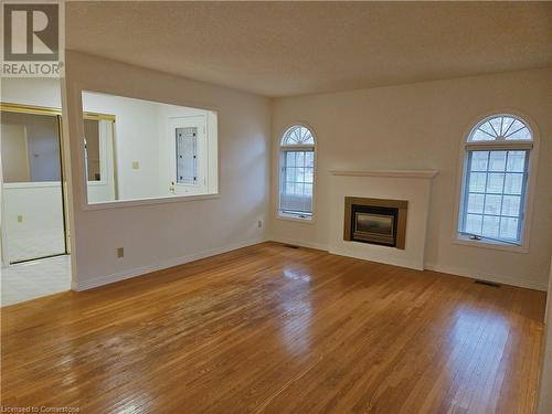 Unfurnished living room featuring plenty of natural light, light hardwood / wood-style floors, and a textured ceiling - 551 Hallmark Drive, Waterloo, ON - Indoor Photo Showing Living Room With Fireplace