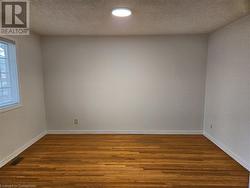 Empty room featuring dark wood-type flooring and a textured ceiling - 