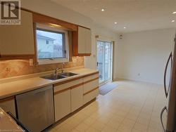 Kitchen with decorative backsplash, a wealth of natural light, sink, and stainless steel dishwasher - 