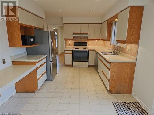 Kitchen with backsplash, extractor fan, sink, electric stove, and stainless steel refrigerator - 551 Hallmark Drive, Waterloo, ON - Indoor Photo Showing Kitchen With Double Sink