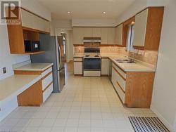 Kitchen with backsplash, extractor fan, sink, electric stove, and stainless steel refrigerator - 