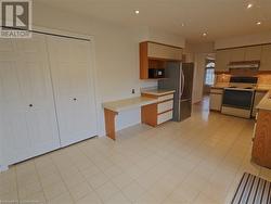 Kitchen with stainless steel refrigerator, white range with electric cooktop, tasteful backsplash, and light tile patterned flooring - 