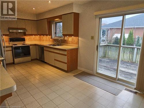 Kitchen with decorative backsplash, premium range hood, stainless steel dishwasher, sink, and white range with electric cooktop - 551 Hallmark Drive, Waterloo, ON - Indoor Photo Showing Kitchen