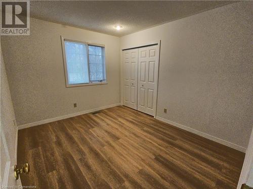 Unfurnished bedroom featuring a closet, dark wood-type flooring, and a textured ceiling - 551 Hallmark Drive, Waterloo, ON - Indoor Photo Showing Other Room