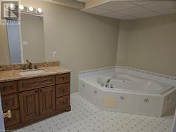 Bathroom with vanity, a relaxing tiled tub, tile patterned floors, and a paneled ceiling - 