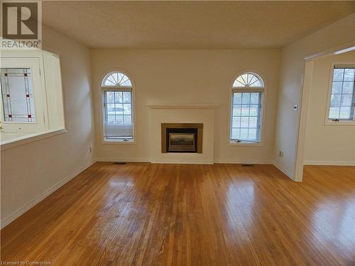 Unfurnished living room featuring light wood-type flooring and a wealth of natural light - 551 Hallmark Drive, Waterloo, ON - Indoor Photo Showing Living Room With Fireplace