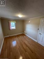 Empty room featuring crown molding, a textured ceiling, and light wood-type flooring - 