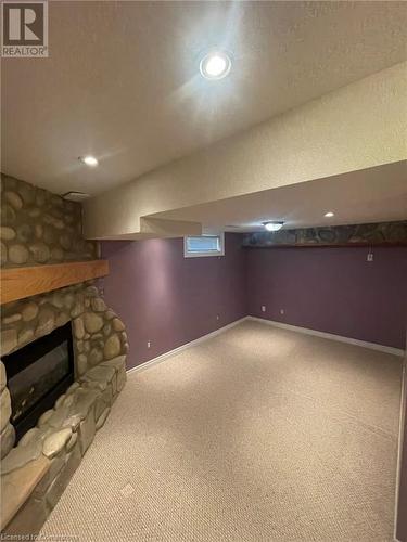 Basement with carpet flooring and a stone fireplace - 126 Peach Blossom Crescent, Kitchener, ON - Indoor With Fireplace