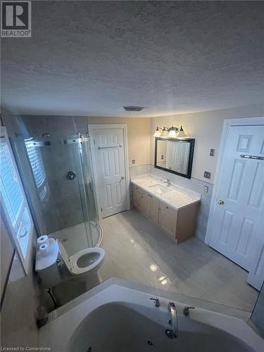 Bathroom with tile patterned flooring, a textured ceiling, toilet, vanity, and a shower with shower door - 126 Peach Blossom Crescent, Kitchener, ON - Indoor