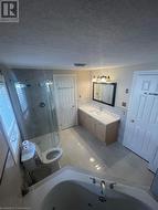 Bathroom with tile patterned flooring, a textured ceiling, toilet, vanity, and a shower with shower door - 