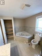 Bathroom with tile patterned floors, tiled bath, and toilet - 