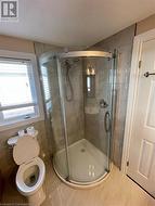 Bathroom featuring tile patterned floors, toilet, and a shower with shower door - 