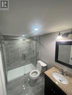 Bathroom featuring vanity, toilet, and a shower with door - 