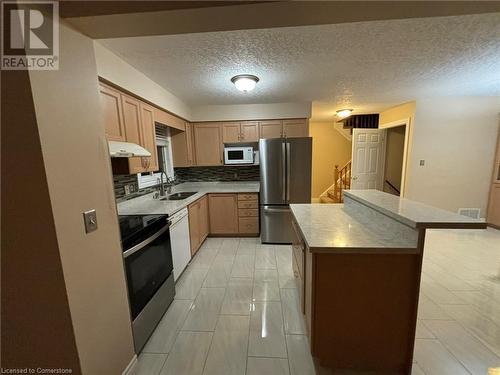 Kitchen featuring decorative backsplash, a textured ceiling, white appliances, sink, and light tile patterned floors - 126 Peach Blossom Crescent, Kitchener, ON - Indoor Photo Showing Kitchen