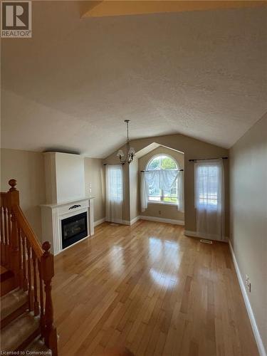 Unfurnished living room with a notable chandelier, lofted ceiling, a textured ceiling, and light hardwood / wood-style flooring - 126 Peach Blossom Crescent, Kitchener, ON - Indoor With Fireplace