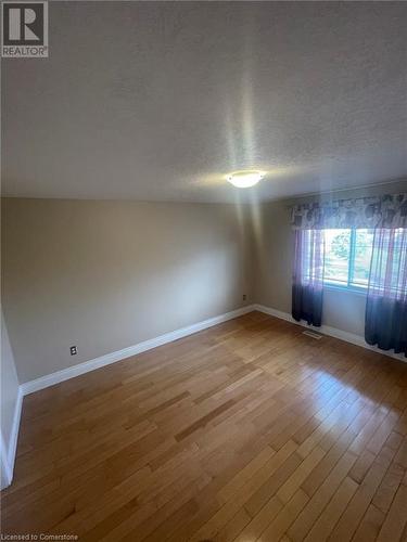 Empty room with a textured ceiling, light hardwood / wood-style floors, and lofted ceiling - 126 Peach Blossom Crescent, Kitchener, ON - Indoor Photo Showing Other Room