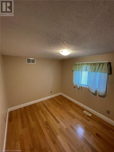 Unfurnished room featuring hardwood / wood-style floors and a textured ceiling - 126 Peach Blossom Crescent, Kitchener, ON - Indoor Photo Showing Other Room