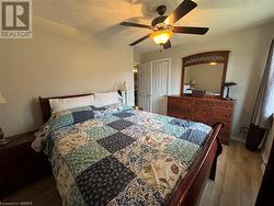 Bedroom featuring ceiling fan, a closet, wood-type flooring, and a textured ceiling - 