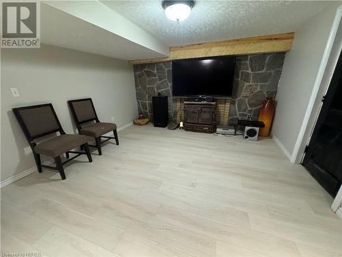 Sitting room featuring light wood-type flooring, a wood stove, and a textured ceiling - 3877 Hwy 17 E, Mattawa, ON - Indoor