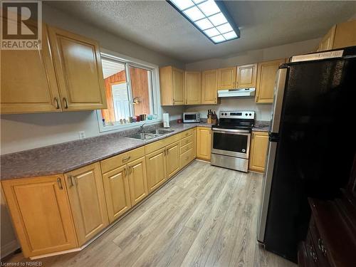 Kitchen featuring sink, stainless steel appliances, a textured ceiling, and light hardwood / wood-style floors - 3877 Hwy 17 E, Mattawa, ON - Indoor Photo Showing Kitchen With Double Sink