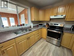 Kitchen featuring electric range, vaulted ceiling, sink, and light hardwood / wood-style flooring - 