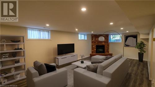 Living room featuring an Electric brick fireplace - Virtually Staged - 228 Byeland Drive, Mount Forest, ON - Indoor Photo Showing Basement