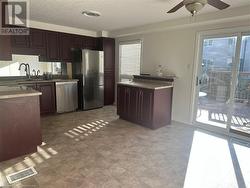 Kitchen with dark brown cabinetry, ceiling fan, sink, and appliances with stainless steel finishes - 