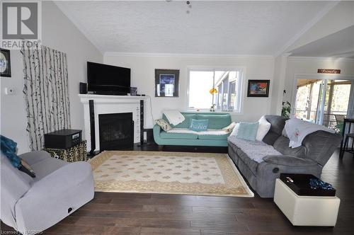 Living room featuring dark engineered hardwood, lofted ceiling, and ornamental molding - 1 Williamson Place, South Bruce Peninsula, ON - Indoor Photo Showing Living Room With Fireplace