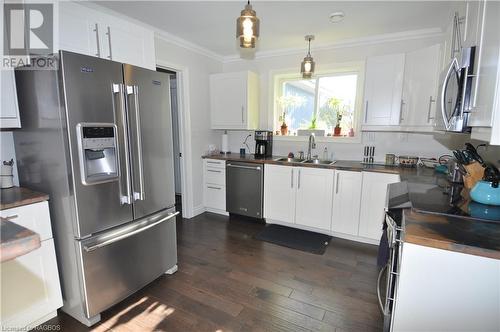 Kitchen featuring white cabinetry, sink, stainless steel appliances, dark engineered hardwood  floors, and ornamental molding - 1 Williamson Place, South Bruce Peninsula, ON - Indoor Photo Showing Kitchen With Double Sink