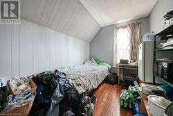 Bedroom featuring lofted ceiling, wooden walls, and dark wood-type flooring - 