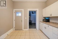 Kitchen with light stone countertops, light tile patterned floors, and white cabinetry - 