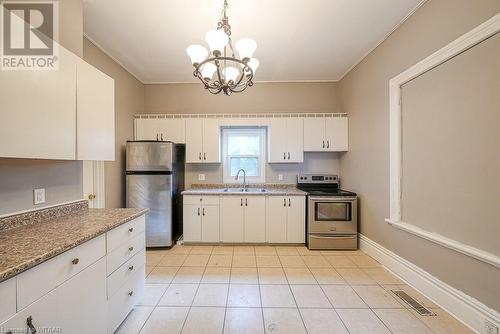 Kitchen featuring sink, appliances with stainless steel finishes, decorative light fixtures, white cabinetry, and a chandelier - 742 Dundas Street, Woodstock, ON - Indoor Photo Showing Kitchen With Double Sink