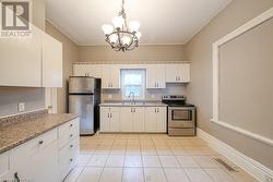 Kitchen featuring sink, appliances with stainless steel finishes, decorative light fixtures, white cabinetry, and a chandelier - 