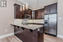 Kitchen with decorative backsplash, appliances with stainless steel finishes, dark brown cabinets, decorative light fixtures - 