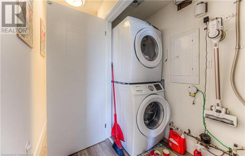 Clothes washing area with electric panel, stacked washer and dryer, and wood-type flooring - 54 Bridge Street West Street W Unit# 6, Kitchener, ON - Indoor Photo Showing Laundry Room