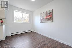 Unfurnished room with baseboard heating and dark wood-type flooring - 