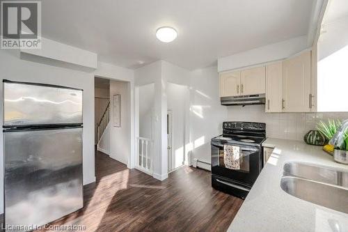 Kitchen featuring backsplash, stainless steel fridge, dark wood-type flooring, and black electric range - 175 Cedarbrae Avenue, Waterloo, ON - Indoor Photo Showing Kitchen With Double Sink