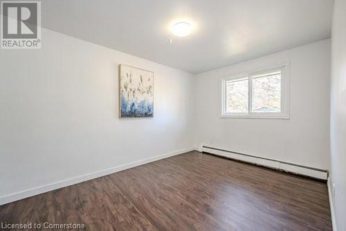 Unfurnished room featuring dark wood-type flooring and a baseboard radiator - 175 Cedarbrae Avenue, Waterloo, ON - Indoor Photo Showing Other Room