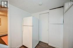 Kitchen with white cabinetry, white fridge, and dark hardwood / wood-style floors - 