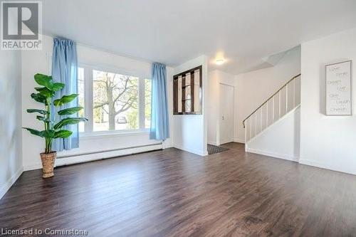 Unfurnished room featuring dark wood-type flooring and a baseboard heating unit - 175 Cedarbrae Avenue, Waterloo, ON - Indoor