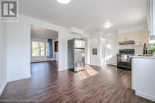 Kitchen with extractor fan, dark wood-type flooring, black electric range, white cabinetry, and stainless steel refrigerator - 175 Cedarbrae Avenue, Waterloo, ON - Indoor Photo Showing Kitchen