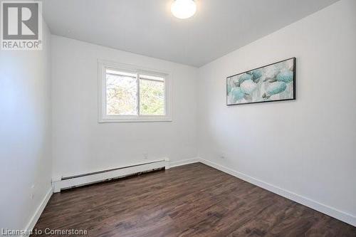 Unfurnished room featuring dark hardwood / wood-style floors and a baseboard heating unit - 175 Cedarbrae Avenue, Waterloo, ON - Indoor Photo Showing Other Room