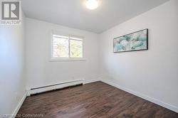 Unfurnished room featuring dark hardwood / wood-style floors and a baseboard heating unit - 