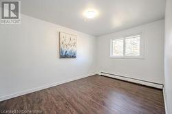 Unfurnished room featuring dark wood-type flooring and a baseboard radiator - 