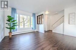 Unfurnished room featuring dark wood-type flooring and a baseboard heating unit - 