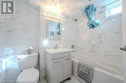 Bathroom featuring a bathing tub, vanity, toilet, and tile walls - 