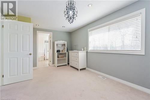 Unfurnished bedroom featuring ensuite bathroom, light carpet, and an inviting chandelier - 613 Black Street, Fergus, ON - Indoor Photo Showing Bedroom