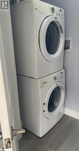 Laundry area with stacked washer / dryer and dark wood-type flooring - 896 John Street Street Unit# B2, Innisfil, ON - Indoor Photo Showing Laundry Room