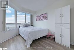 Bedroom with light wood-type flooring, a water view, and multiple windows - 